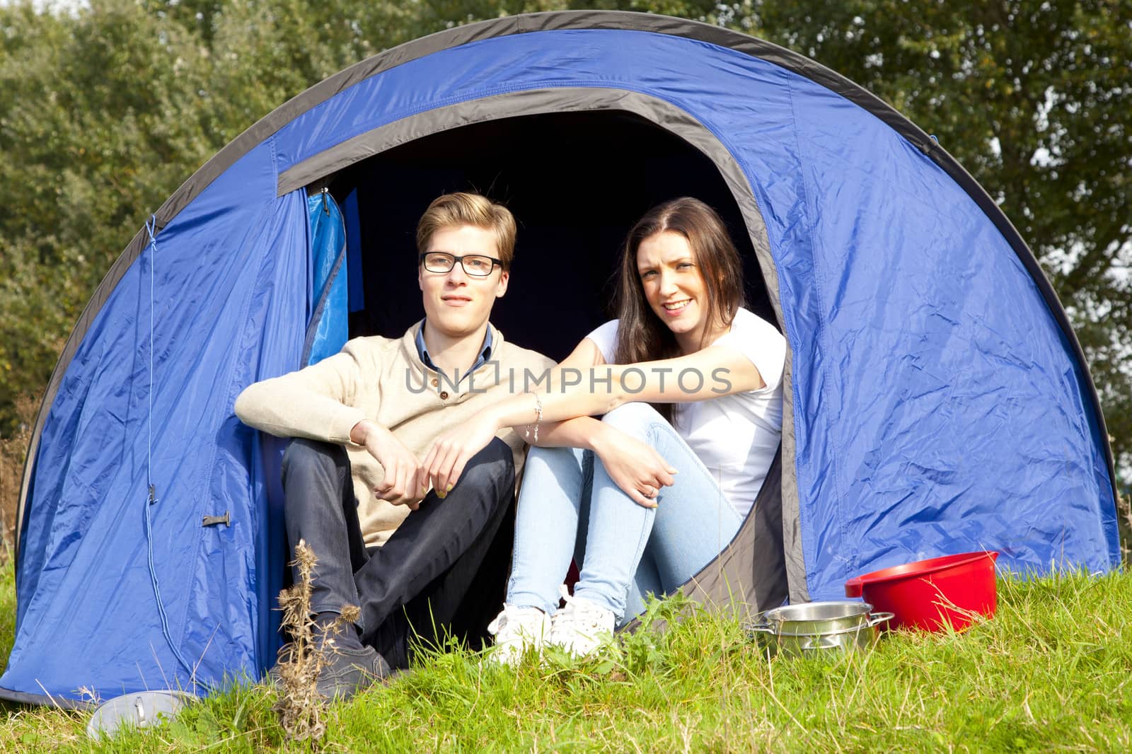 Young man and woman camping with blue tent