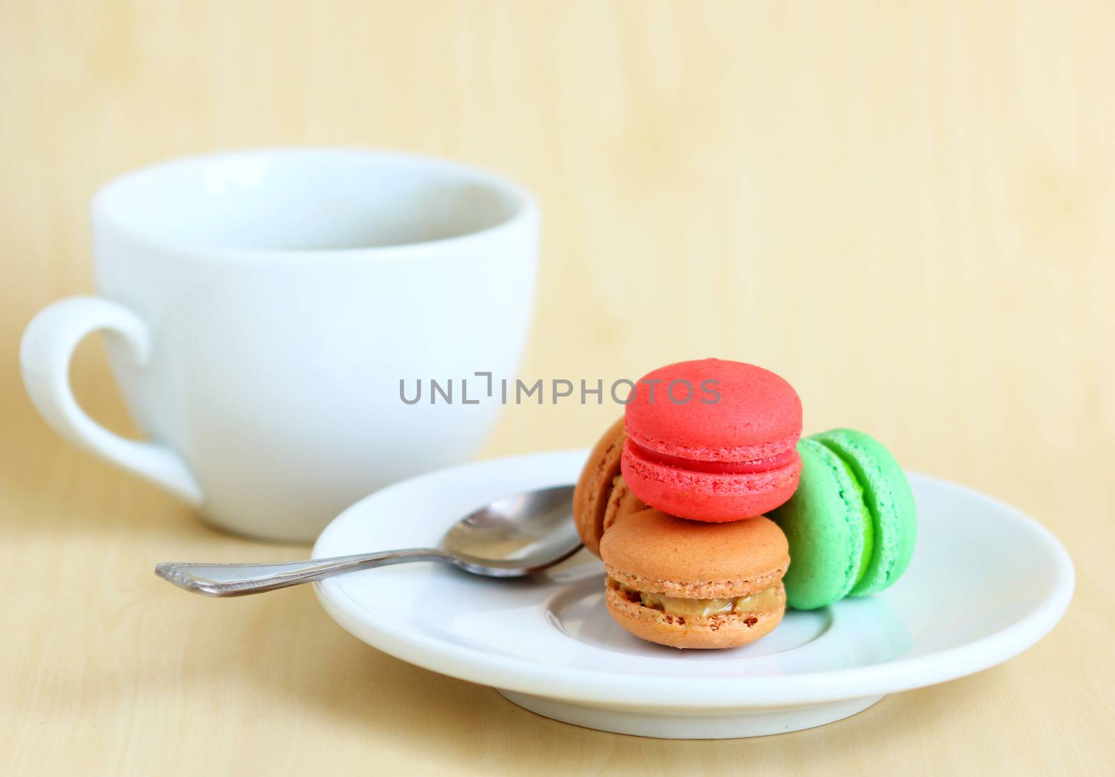 Colorful macaroons and a cup of coffee with spoon by nuchylee