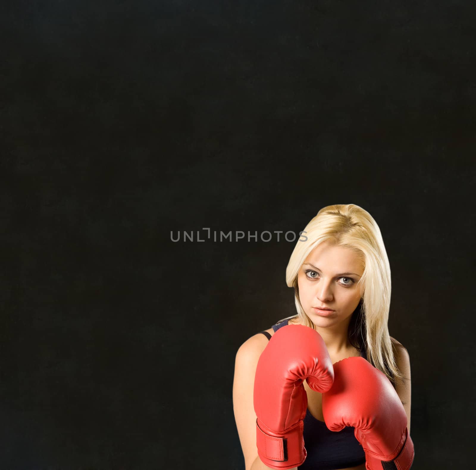 Beautiful young woman training with boxing gloves on blackboard background by alistaircotton