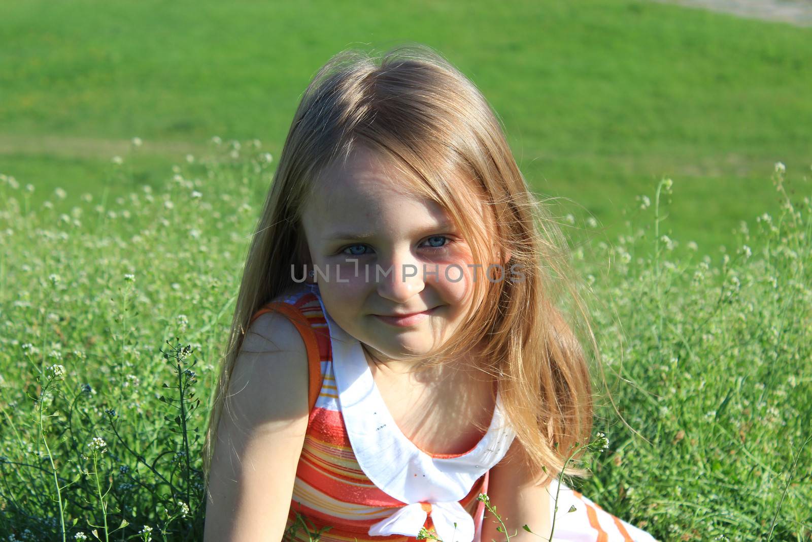 little fashionable girl lying on the green grass