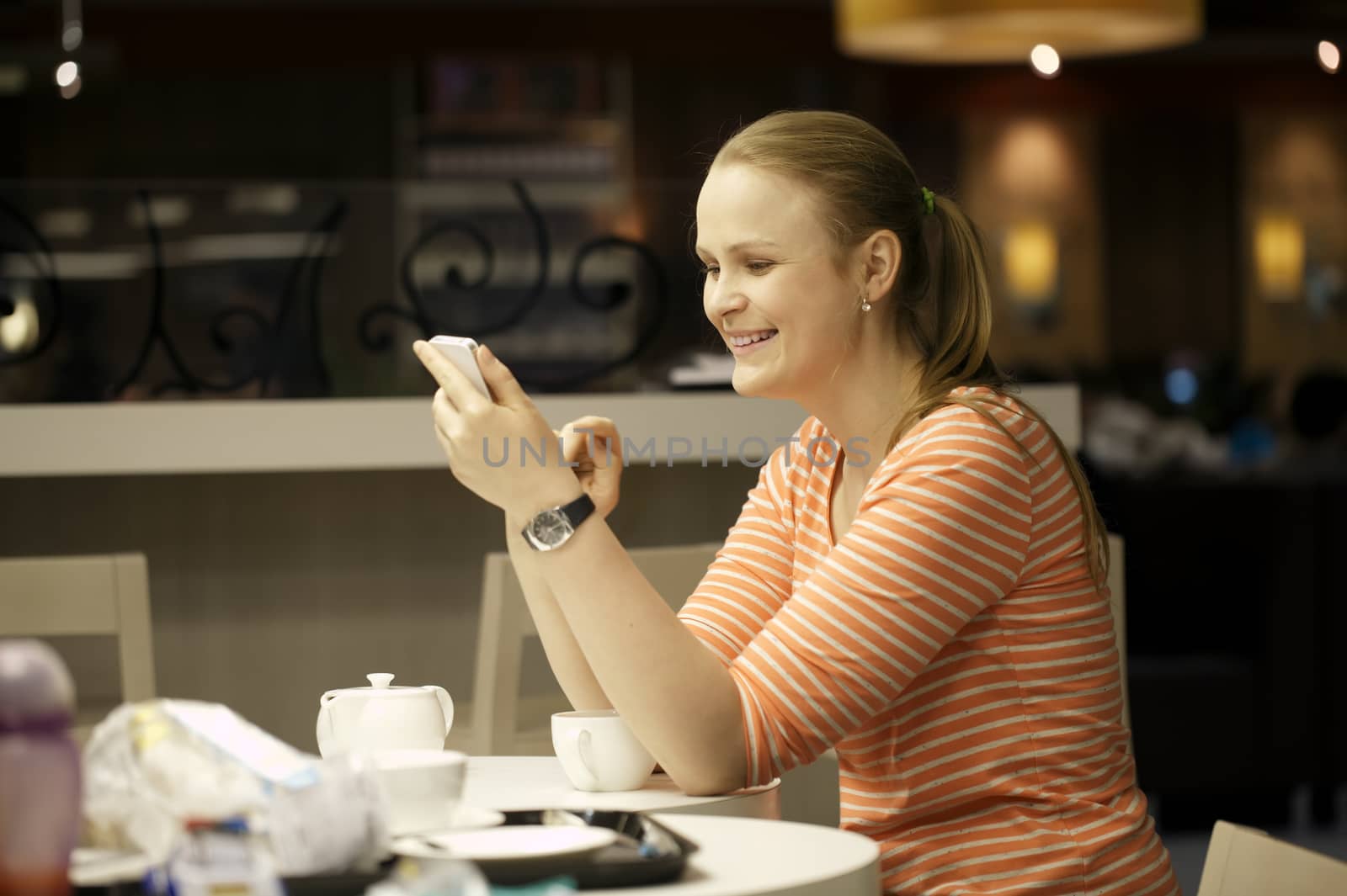 Young beautiful woman chatting on smartphone sitting in cafe