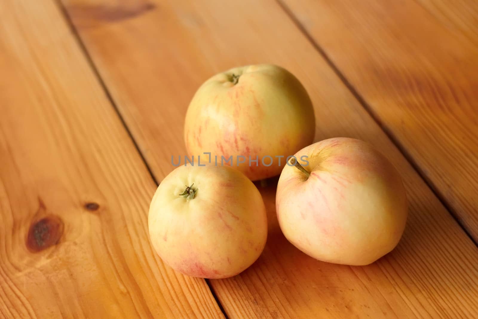 Three ripe apples on a lacquered wooden table