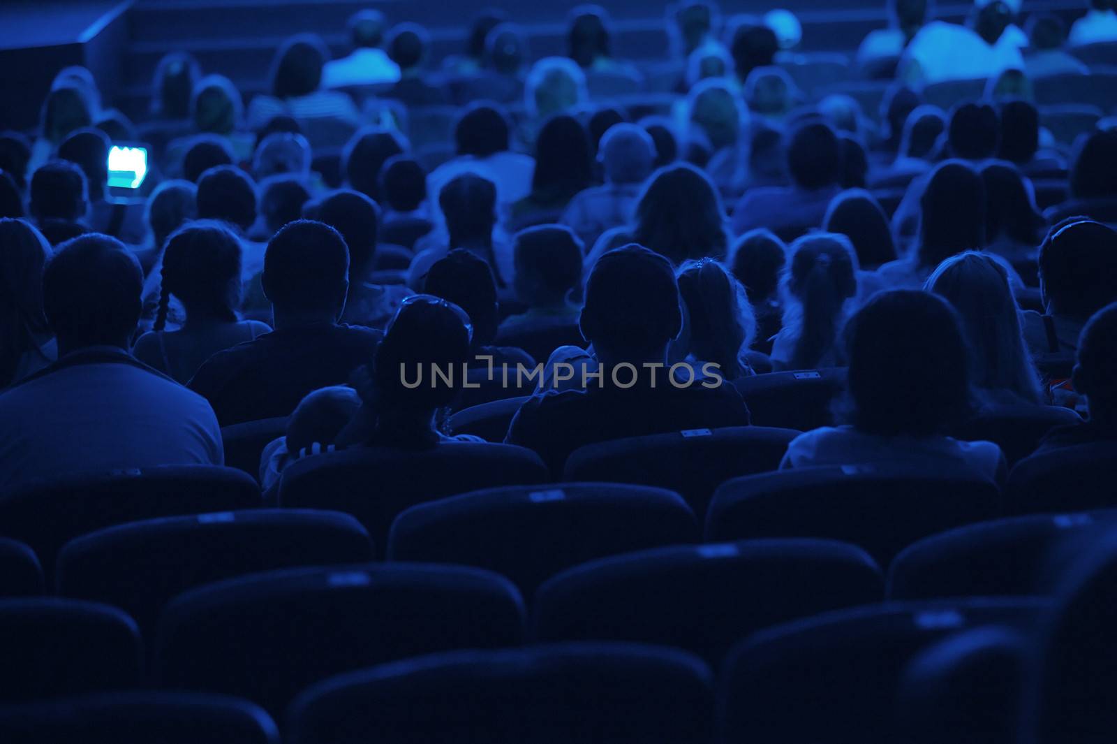 Audience in the cinema. Silhouette shot from back in blue light.