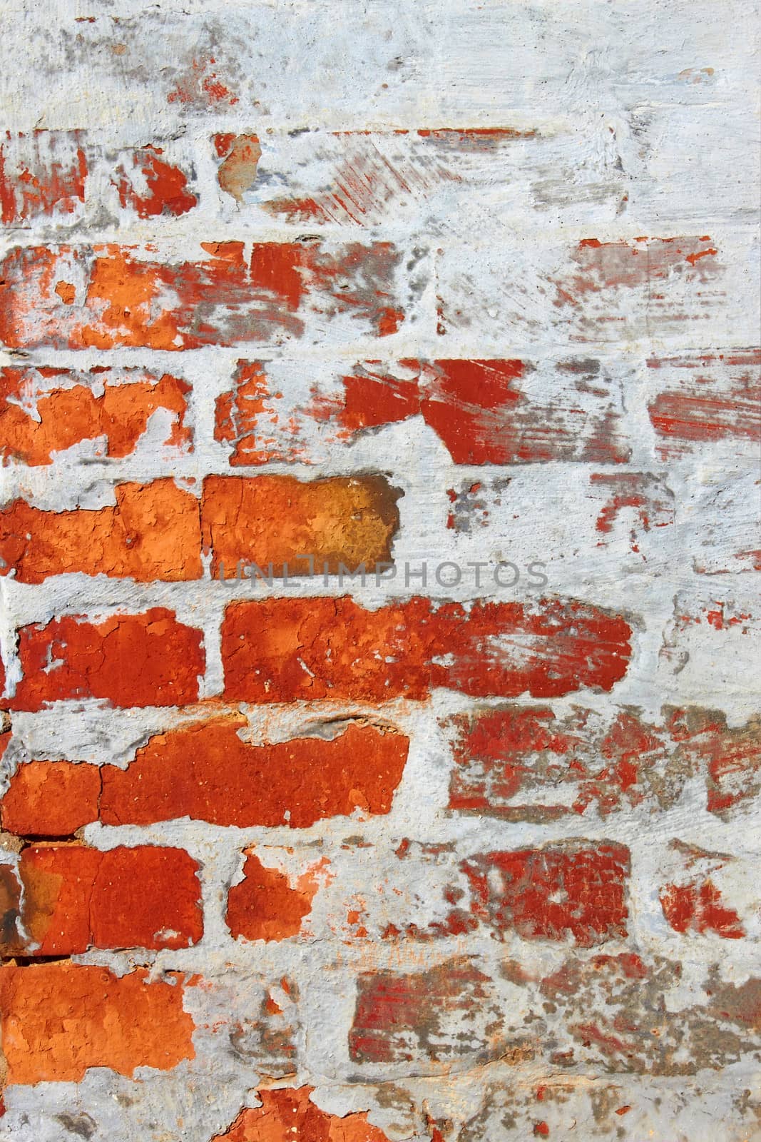 Old wall from a red brick partially covered by cement mixed with lime
