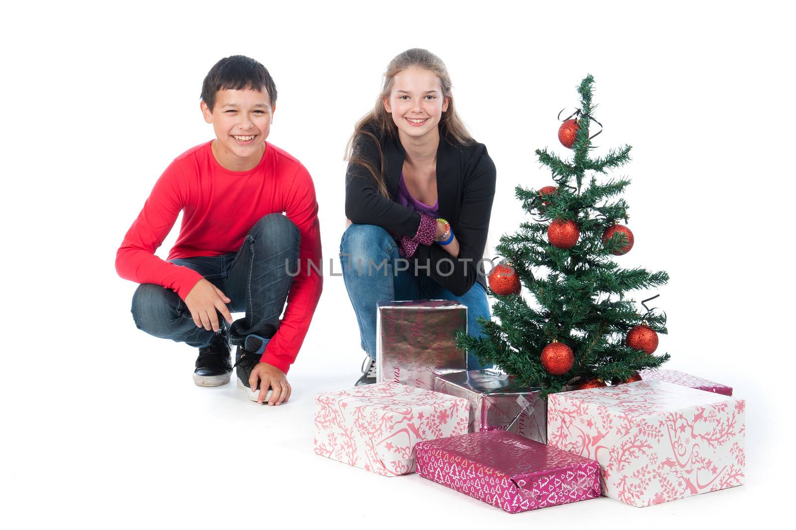 a boy and a girl, dressed to celebrate Christmas, with a lot of presents