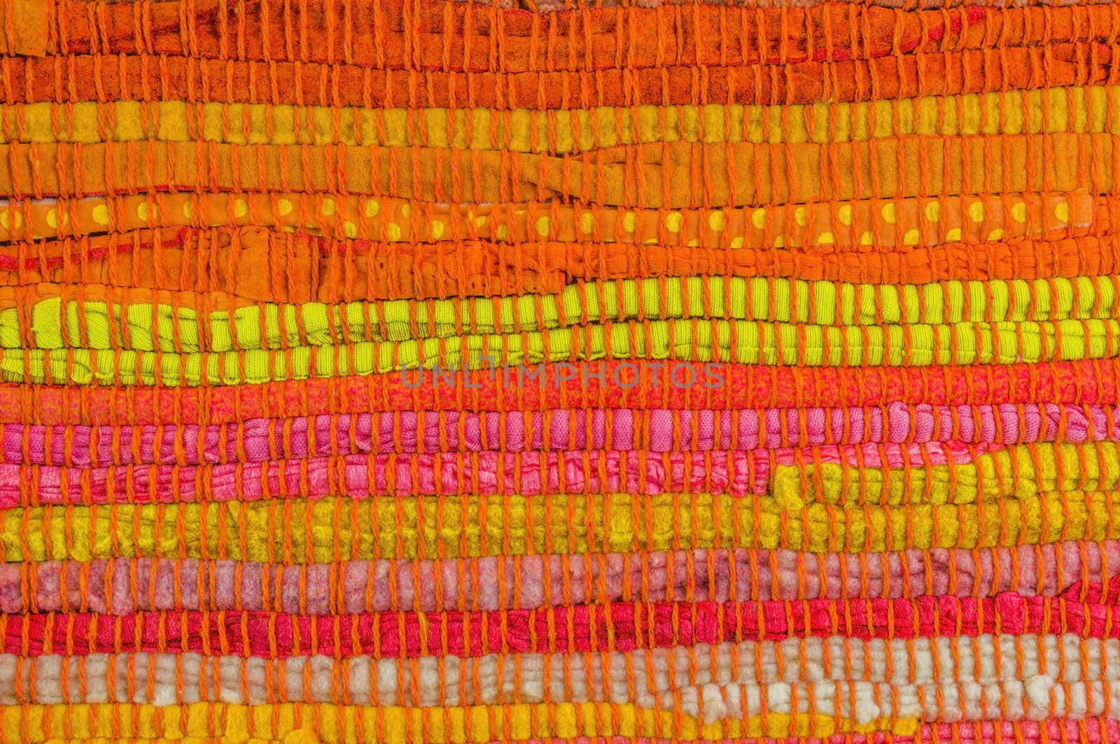 Textile background in red, yellow, orange, pink and green manually weaved