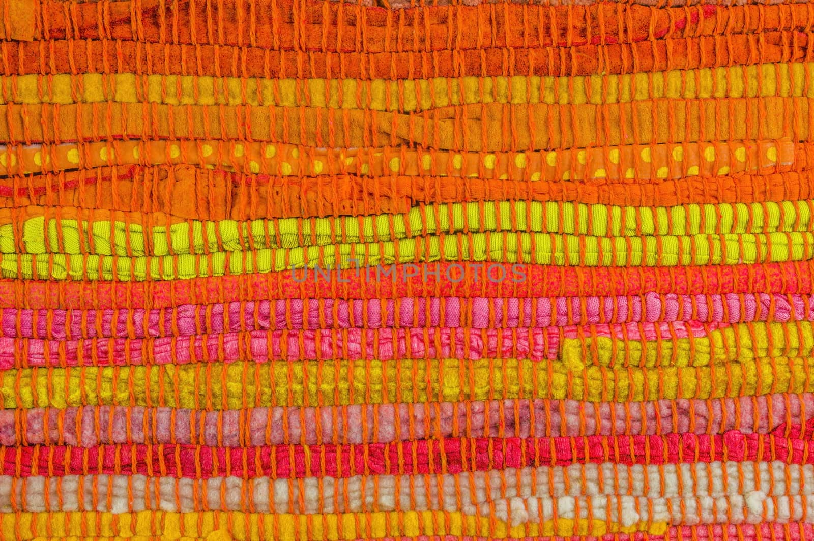 Textile background in red, yellow, orange, pink and green manually weaved