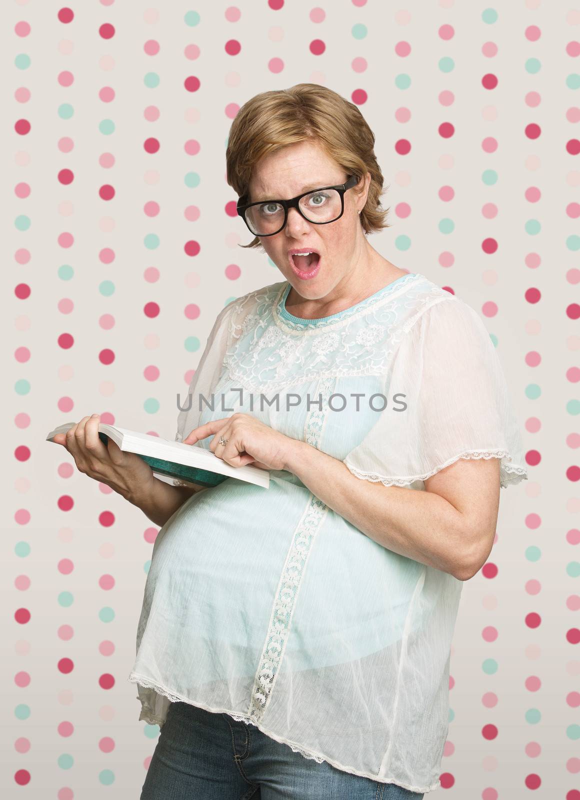 Astonished single pregnant female pointing at a book