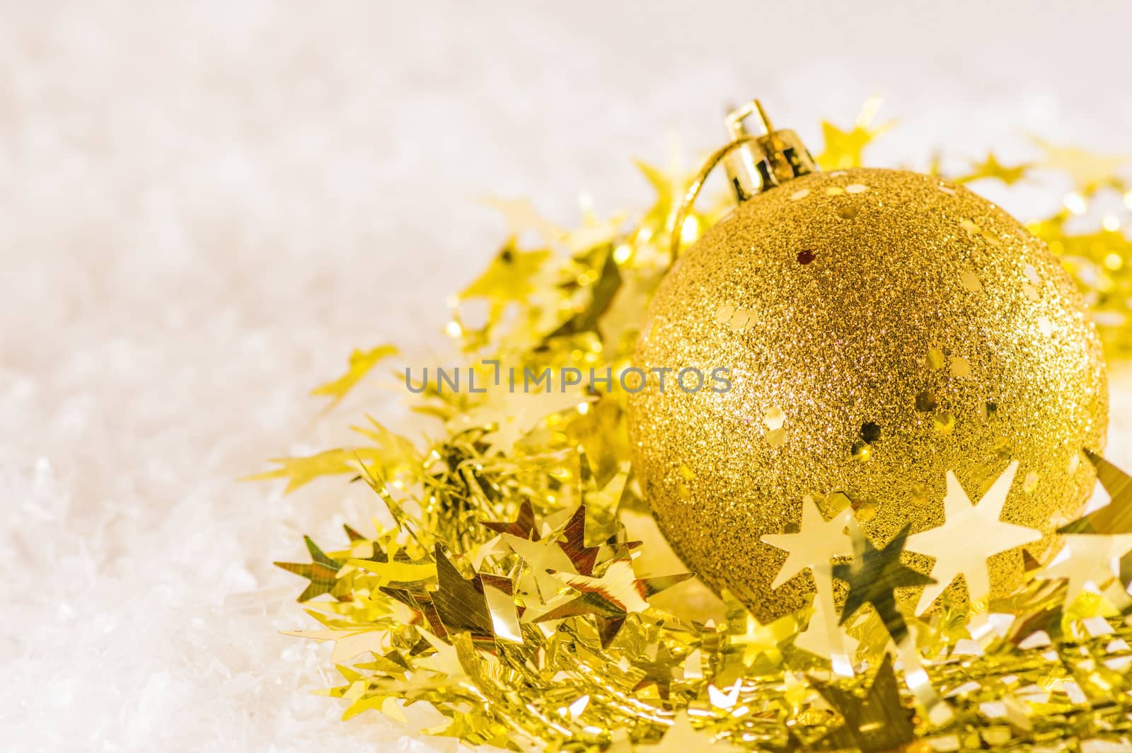 Golden Christmas decoration and golden tinsel on artificial snow background