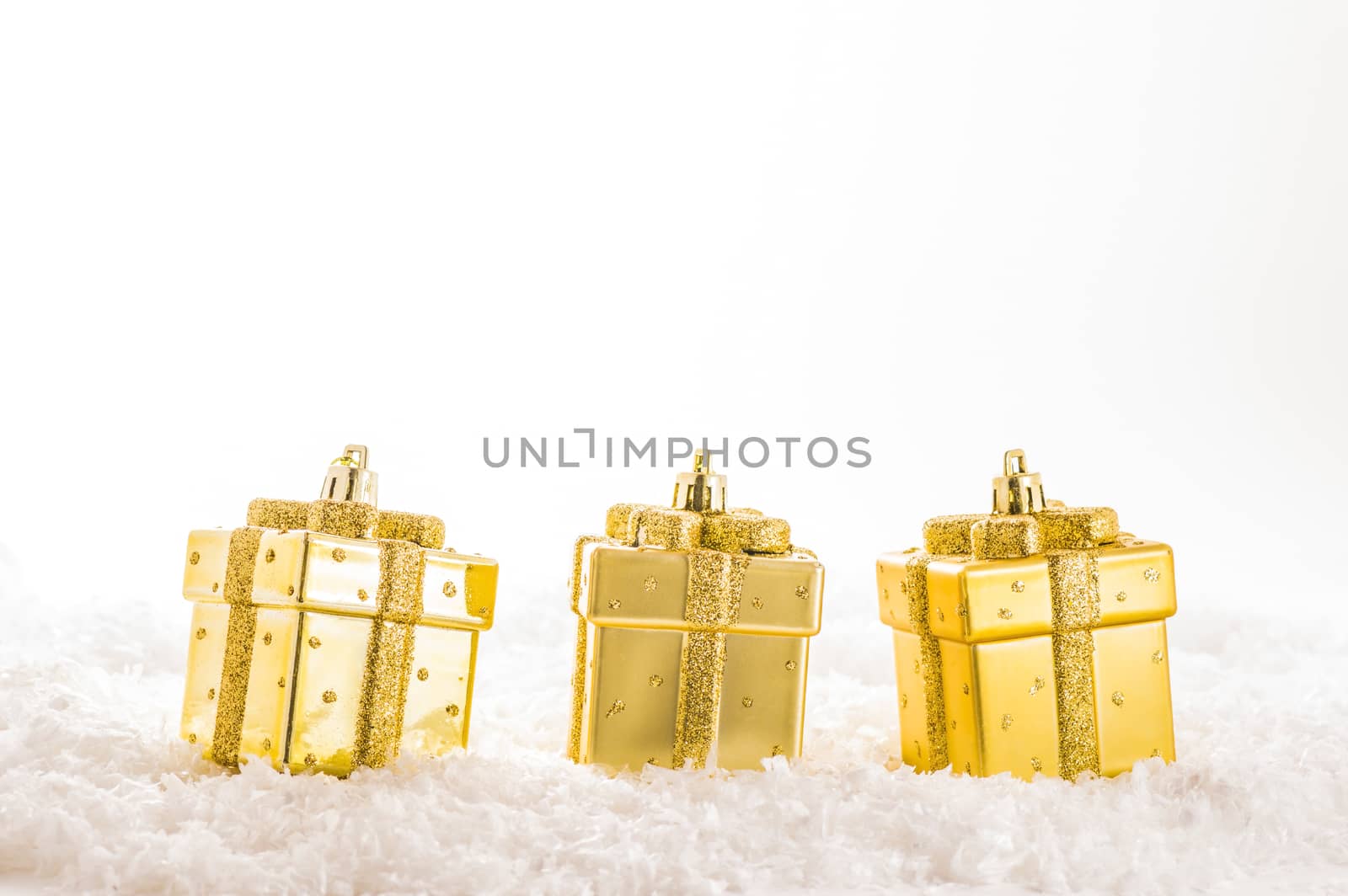 Three golden christmas decorations on artificial snow