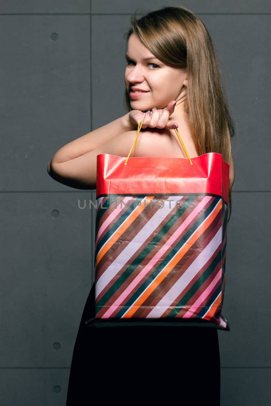 beautiful young woman with colored shopping bags over blue background