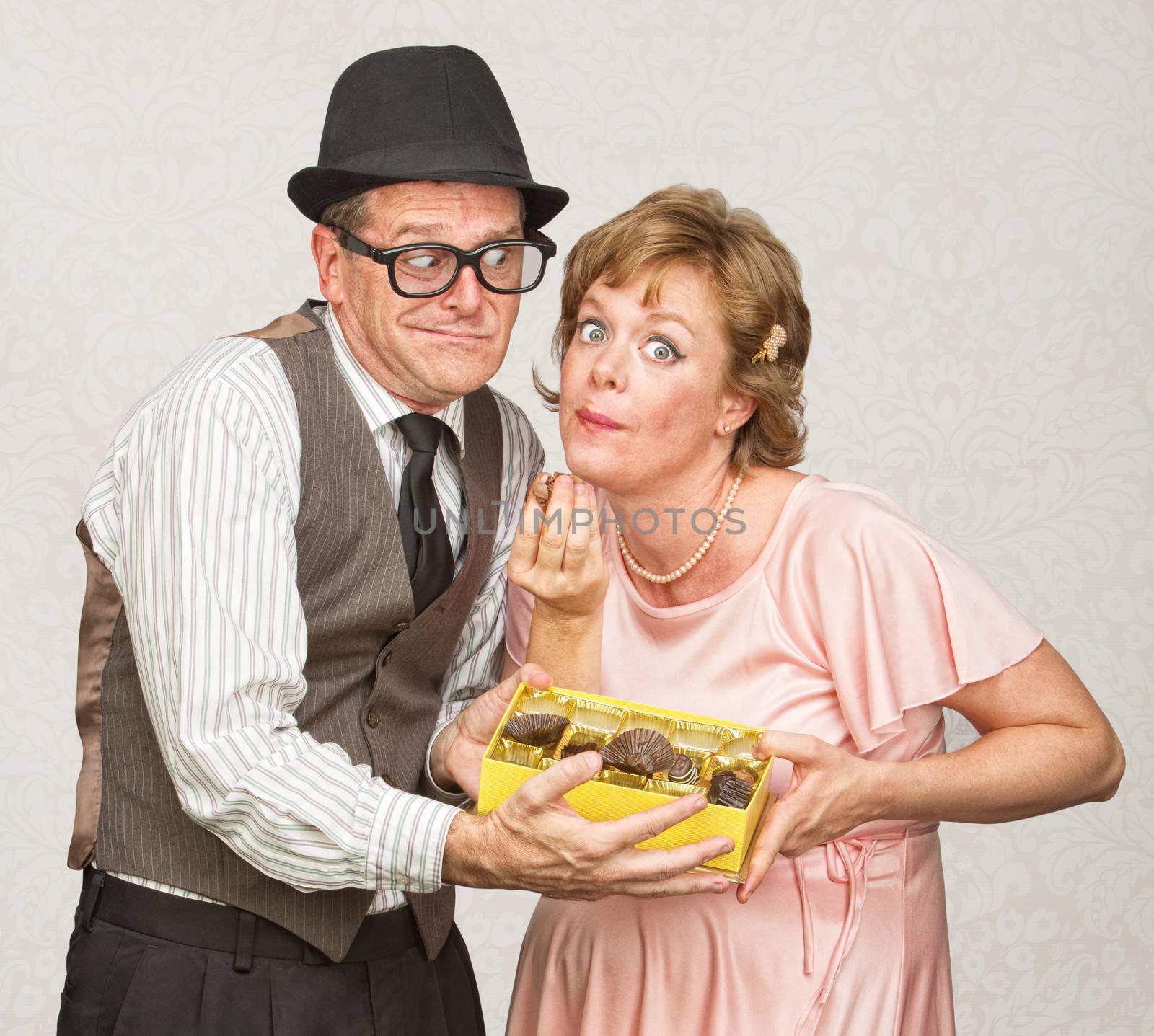 Awkward man holding box of chocolate for pregnant woman