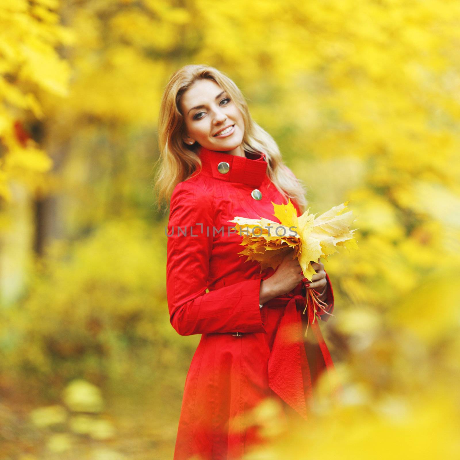 Young woman holding a bunch of autumn leaves