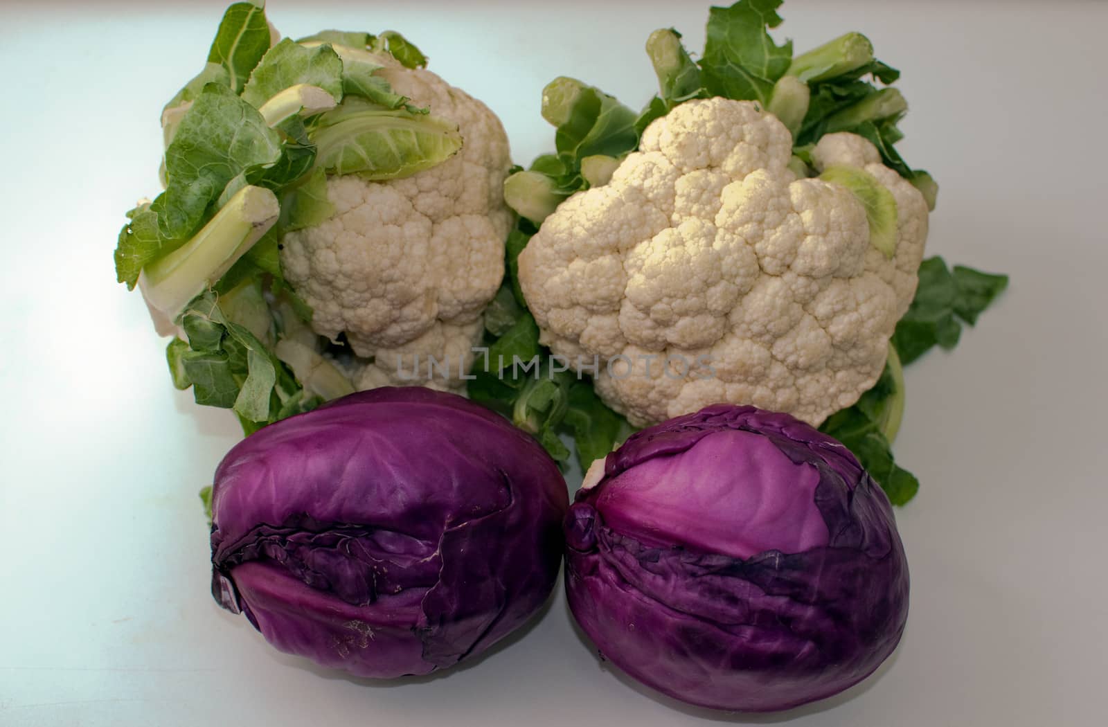 Freshly cut red and cauliflower cabbage isolated on white .