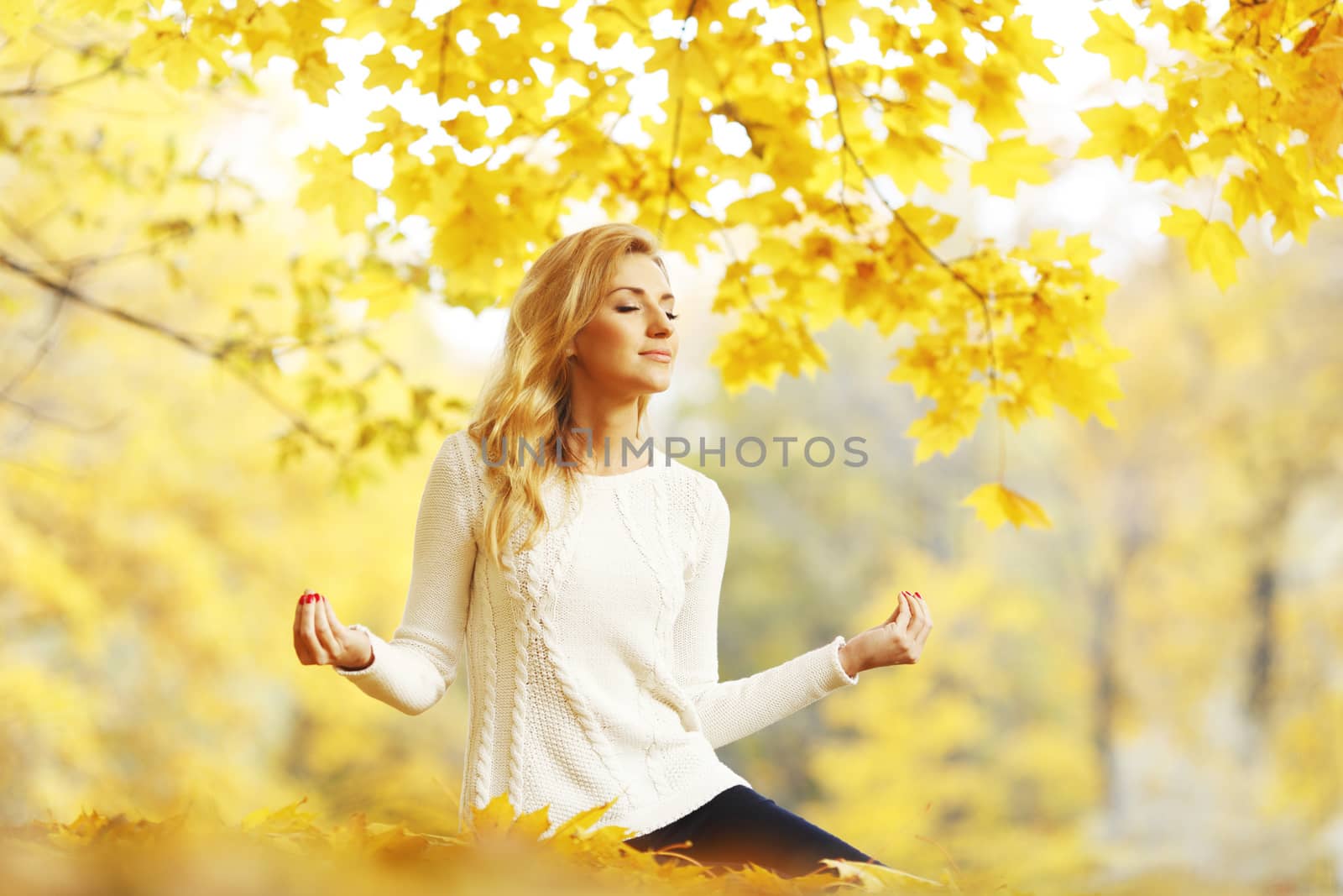 Beautiful young woman meditating outdoors in autumn park