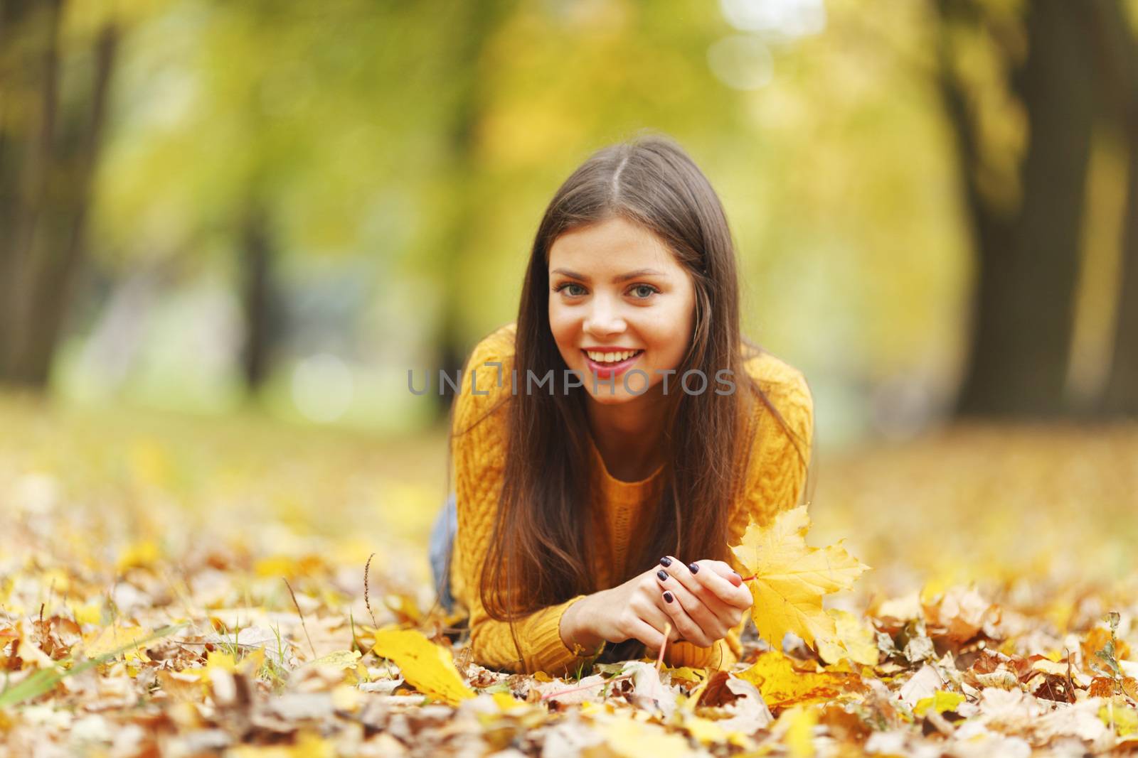 Girl laying on leafs in the autumn park