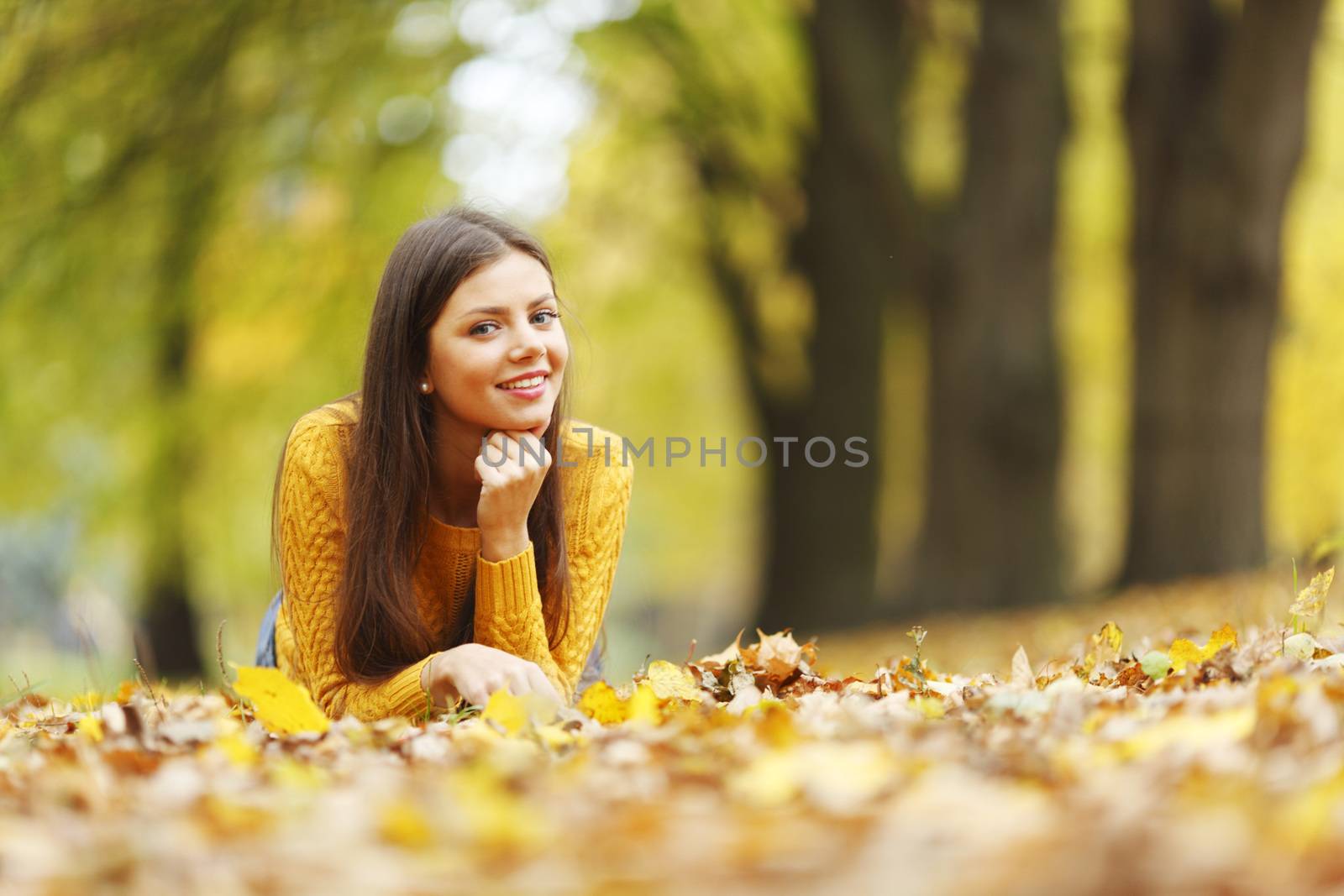 Girl laying on leafs in the autumn park