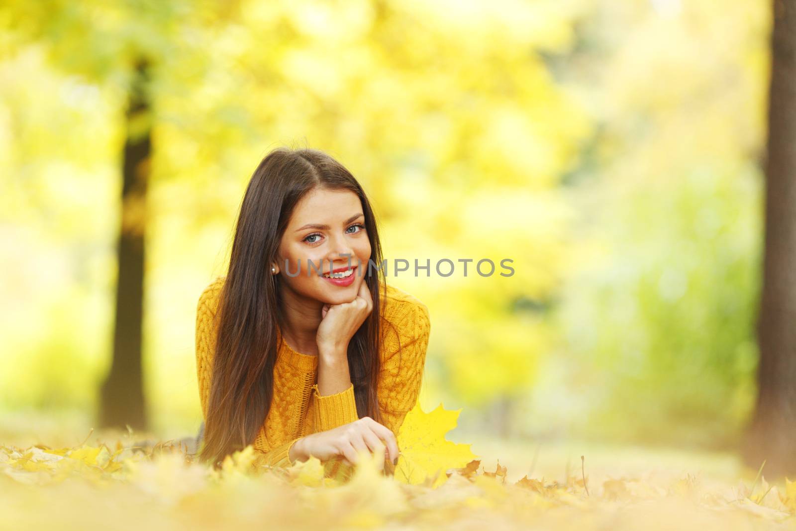 Girl laying on leafs in the autumn park