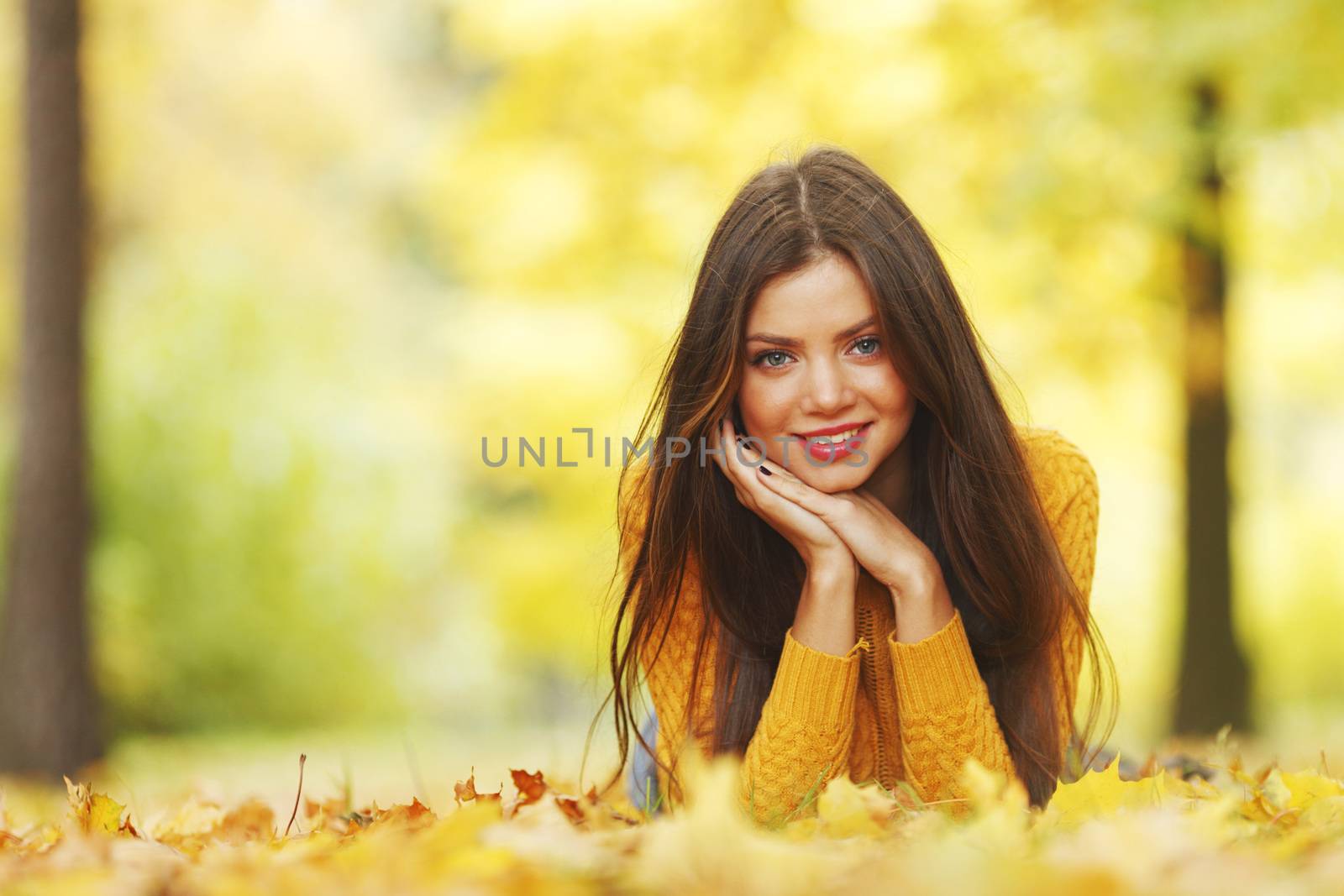 Girl laying on leafs in the autumn park