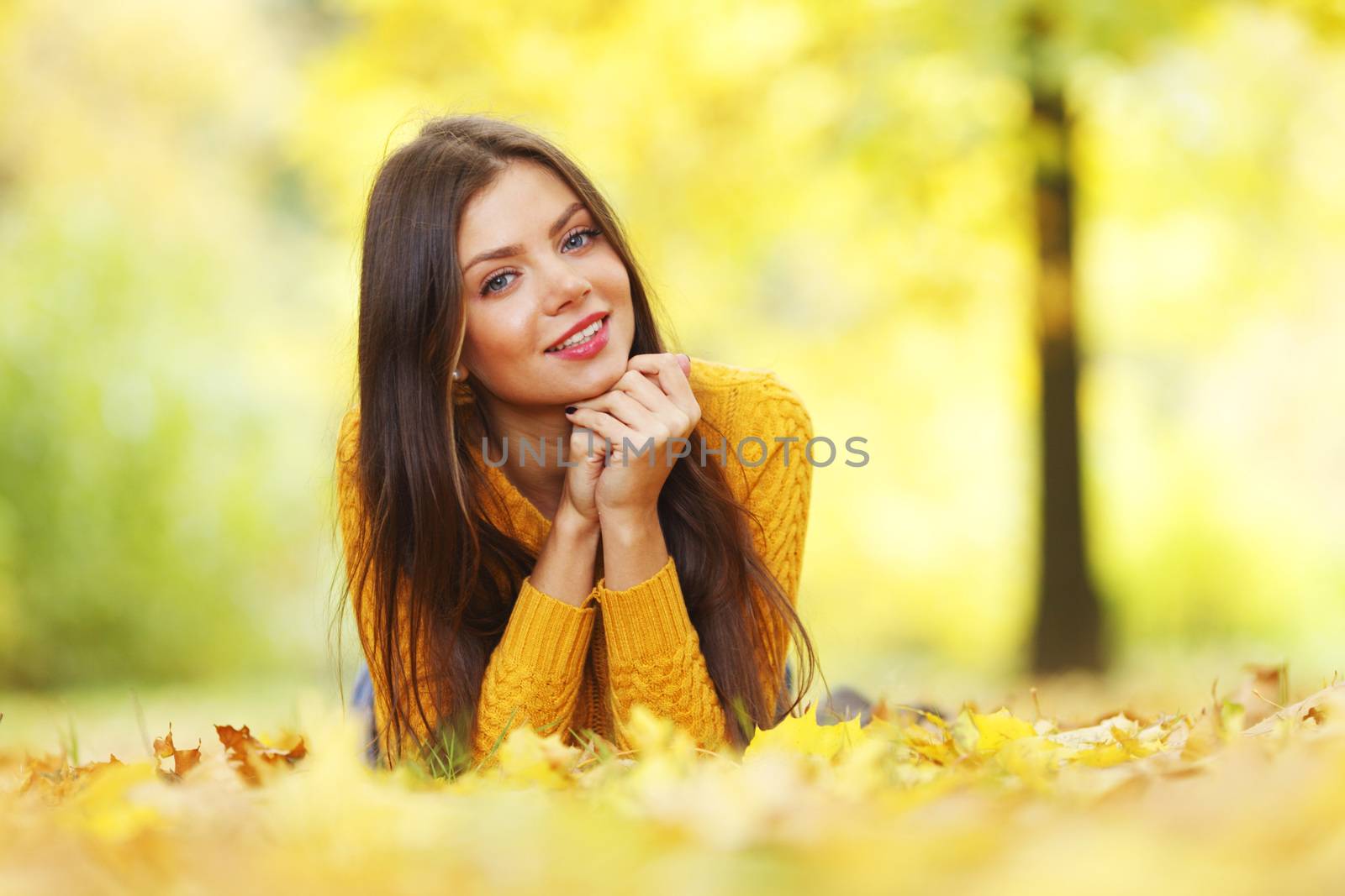 Girl laying on leafs in the autumn park