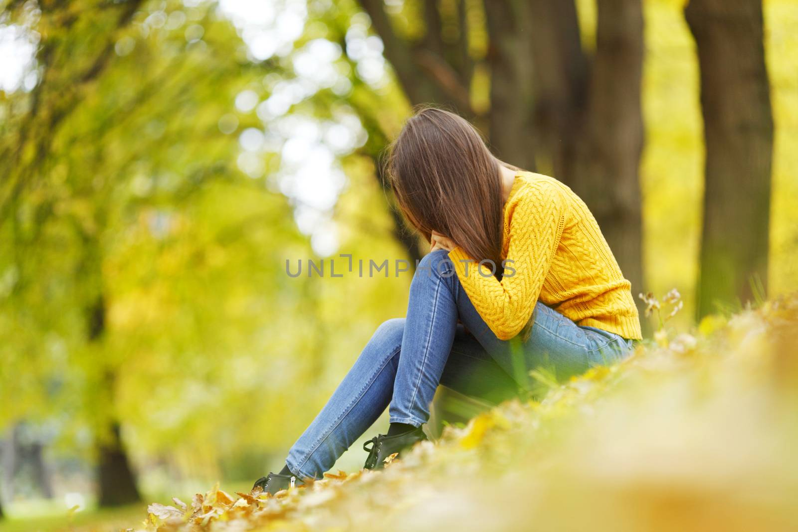 Beautiful woman sitting on autumn leaves in park