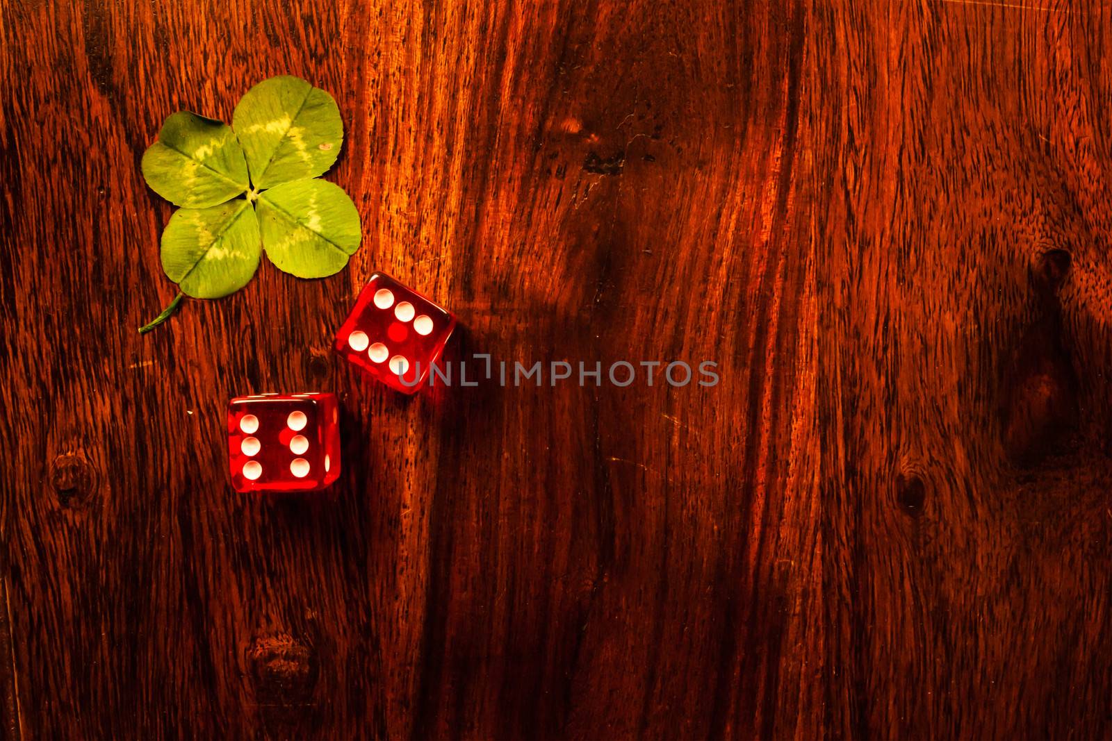 Two red dices with a luckycharm four-leaf clover