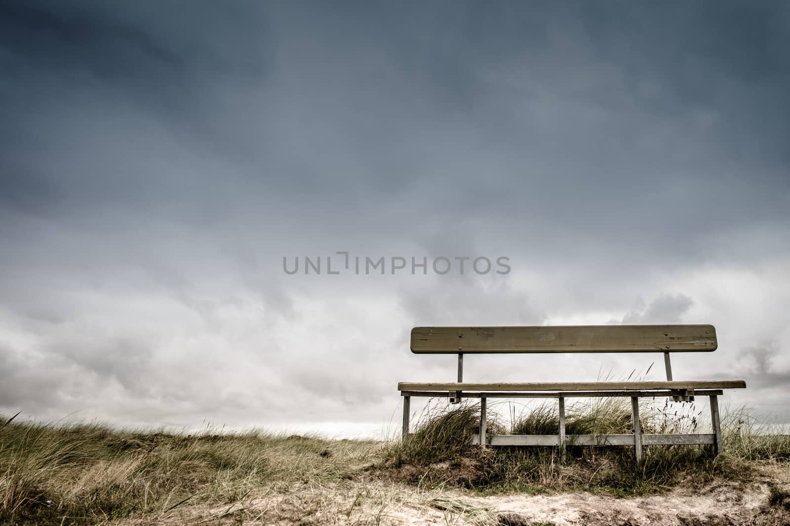 Empty wooden bench in cloudy weather