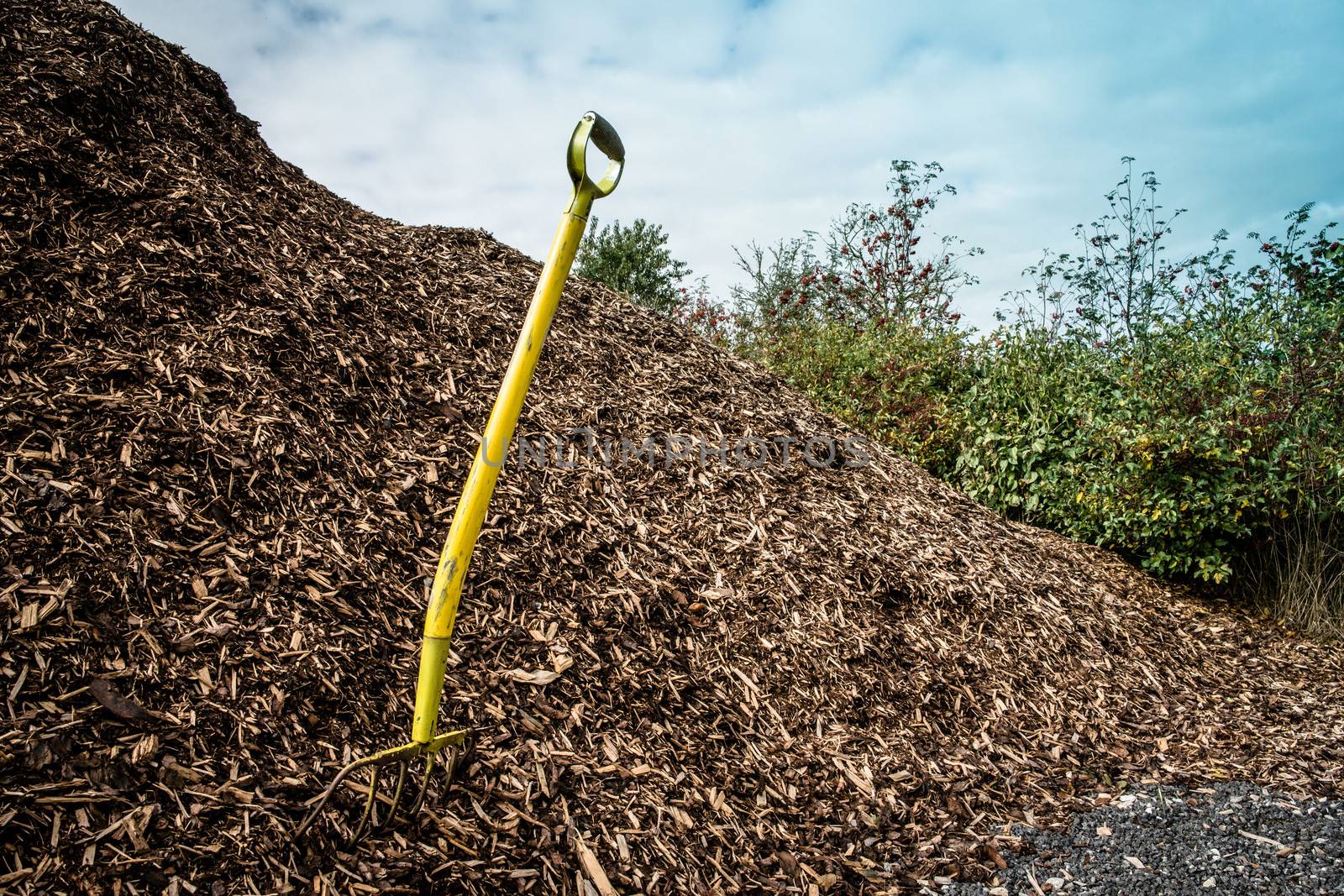 Yellow shovel in a big pile of mulch