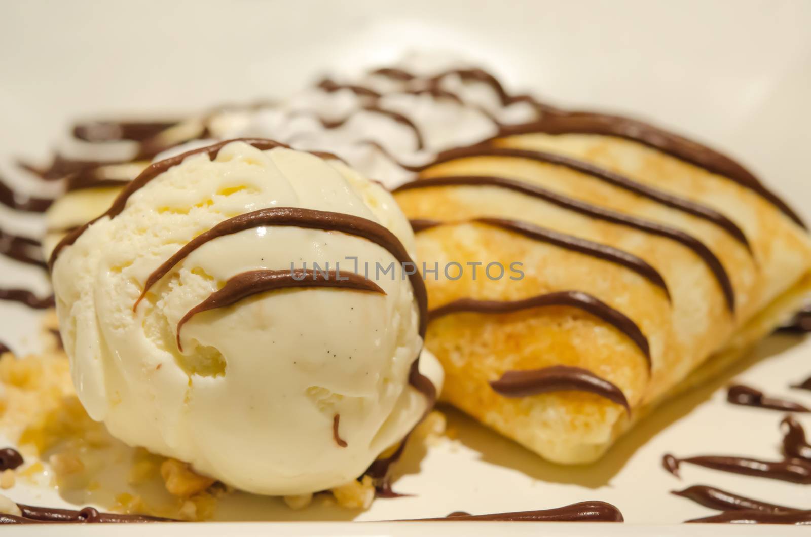 close up vanilla ice cream and crepes with banana , chocolate sauce  served with whipping cream
