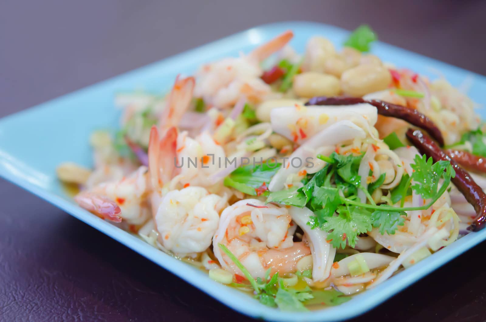 close up spicy  salad  with  boiled shrimp , lemongrass , fried chili  and fresh vegetable on blue dish