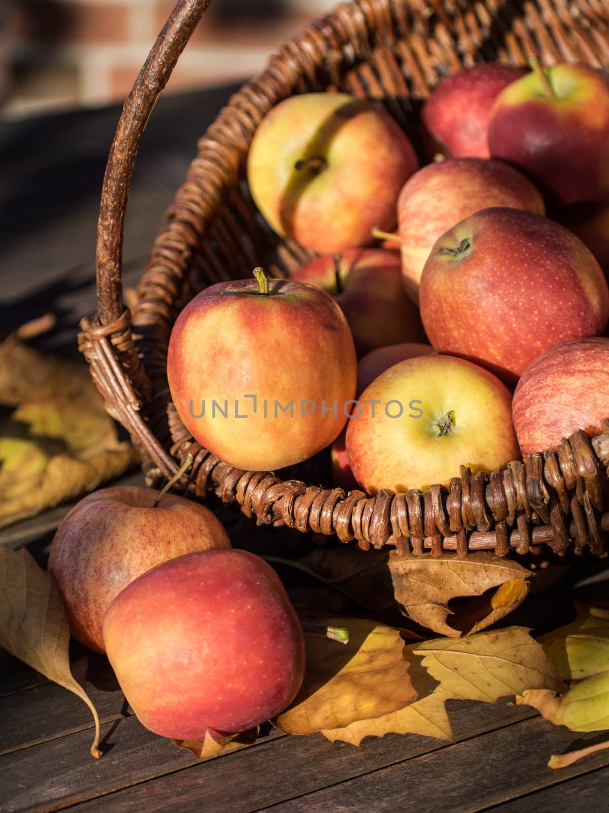 Wicker basket with red apples on a wooden table.