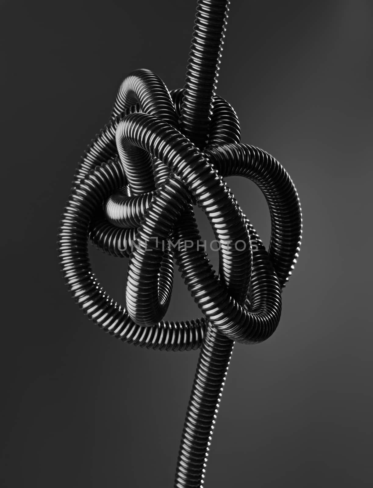 Black and white image of a black tangled flexible hose.