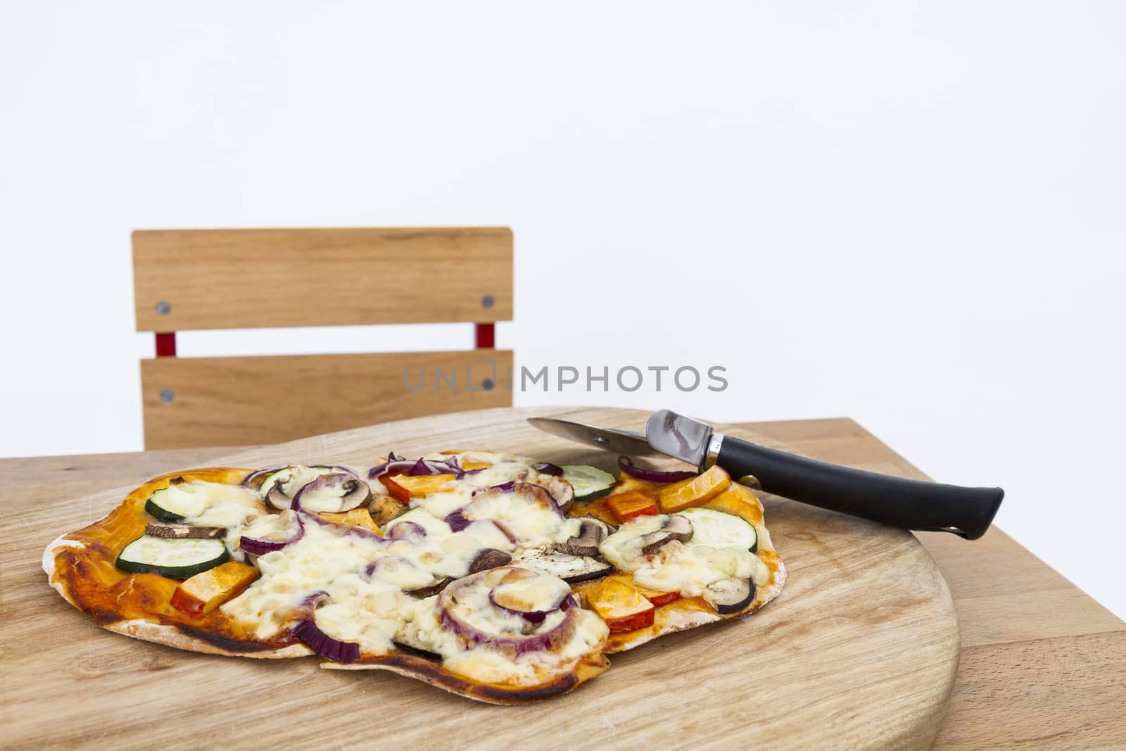 homemade pizza with cutter on small desk in light grey background
