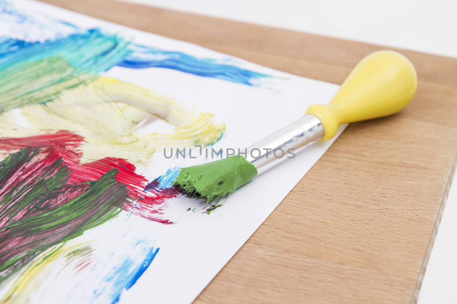 green paint with paint brush  and paper on wooden table