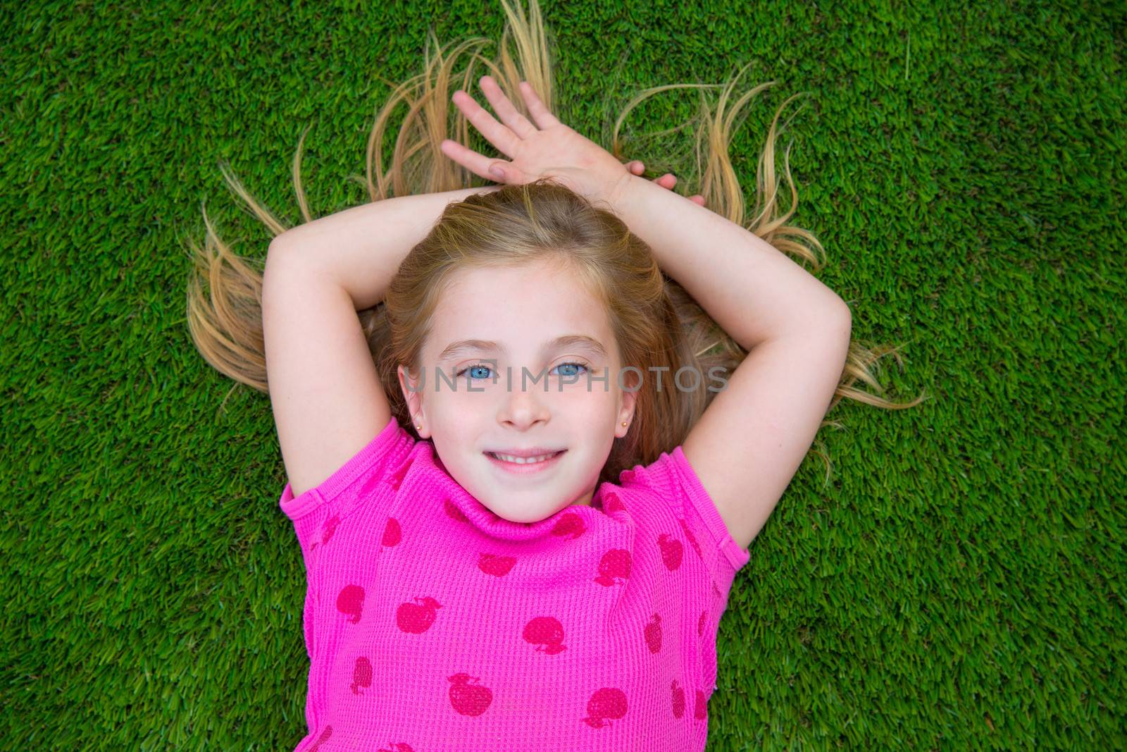 Beautiful blond kid children girl smiling lying on grass by lunamarina