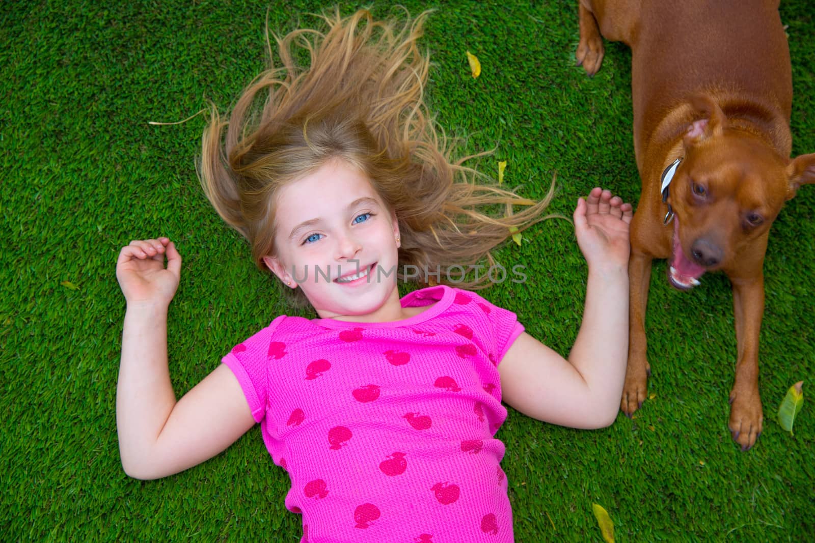 Beautiful blond kid children girl smiling lying on grass by lunamarina