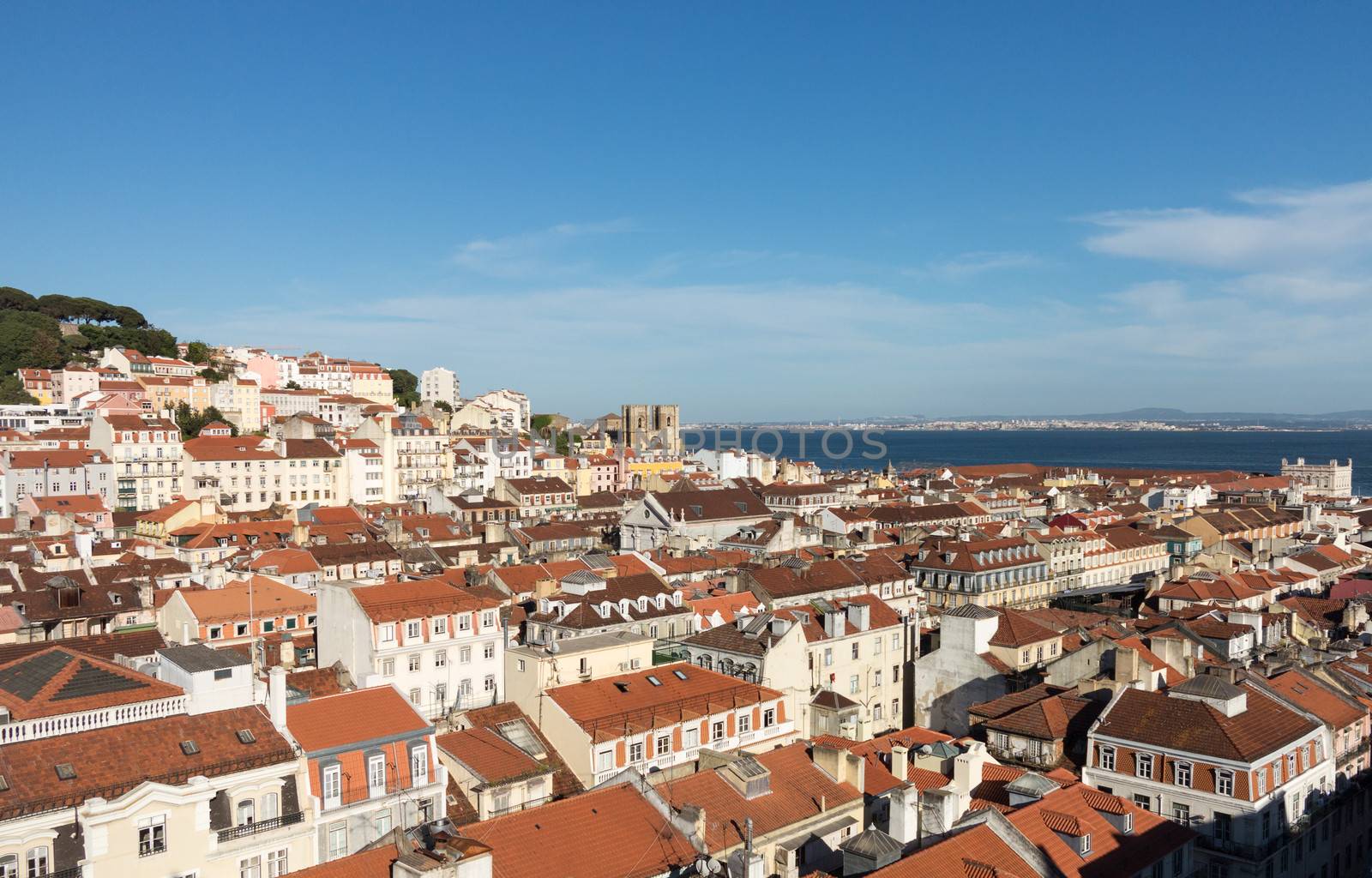 Old houses and roofs in cityscape of Alfama district of Lisbon in Portugal with the coast in the distance