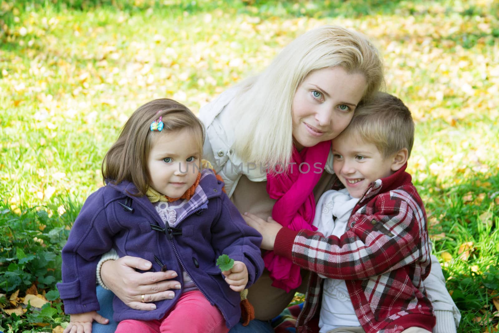 Happy mother and two children on autumn grass