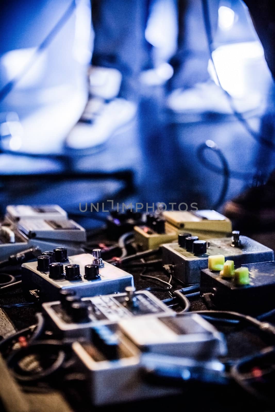 Guitar Pedals on a Stage with Live Band Performing During a Show. Low light image with copyspace