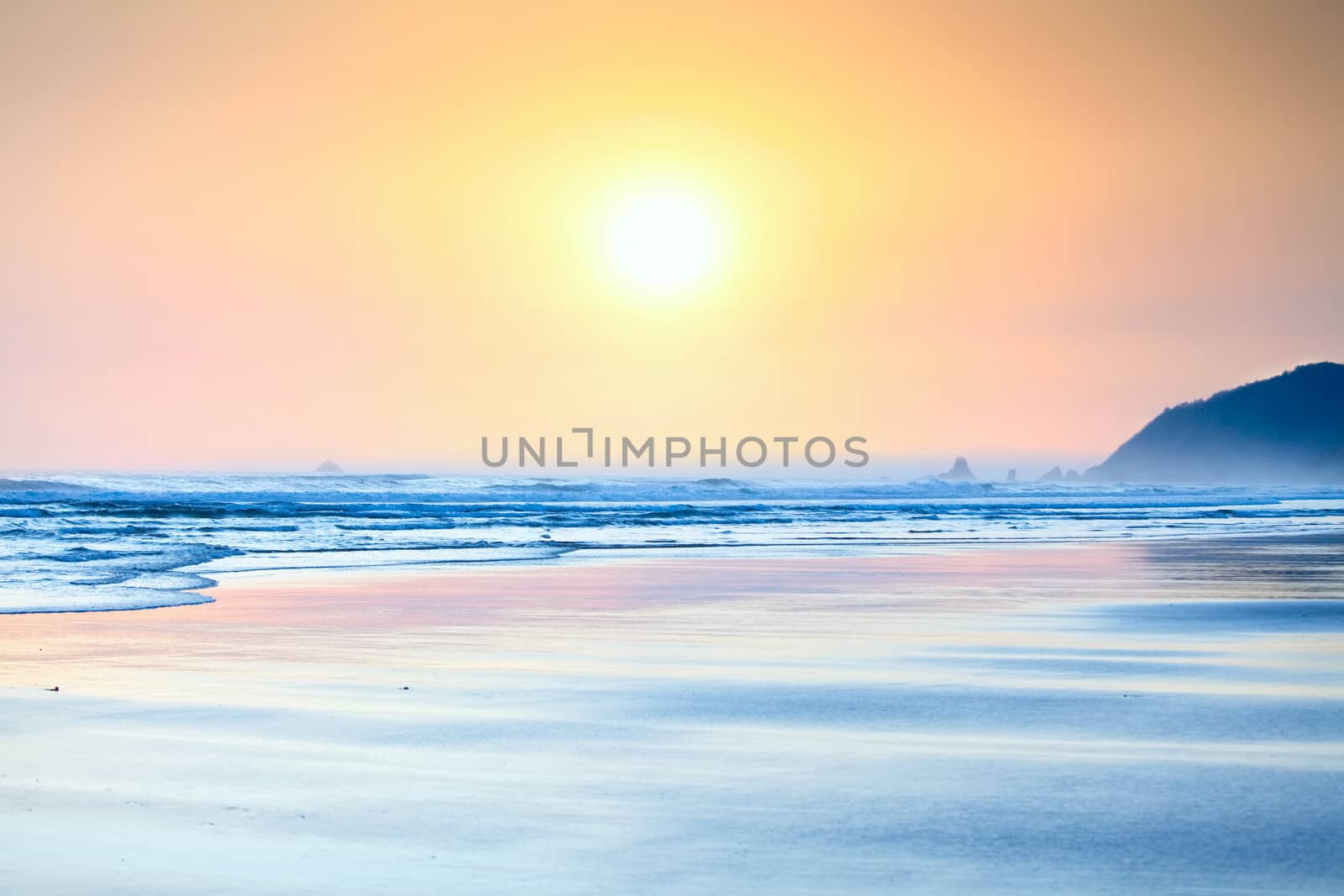 Beautiful yellow orange sunset over   gentle waves washing up on beach