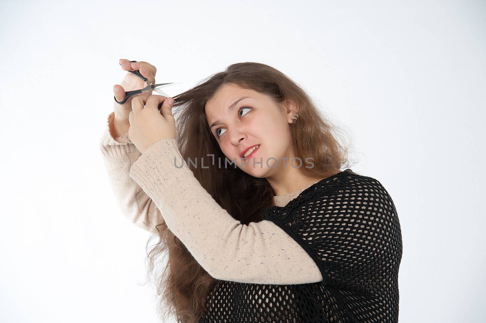 woman mows split ends of hair with scissors