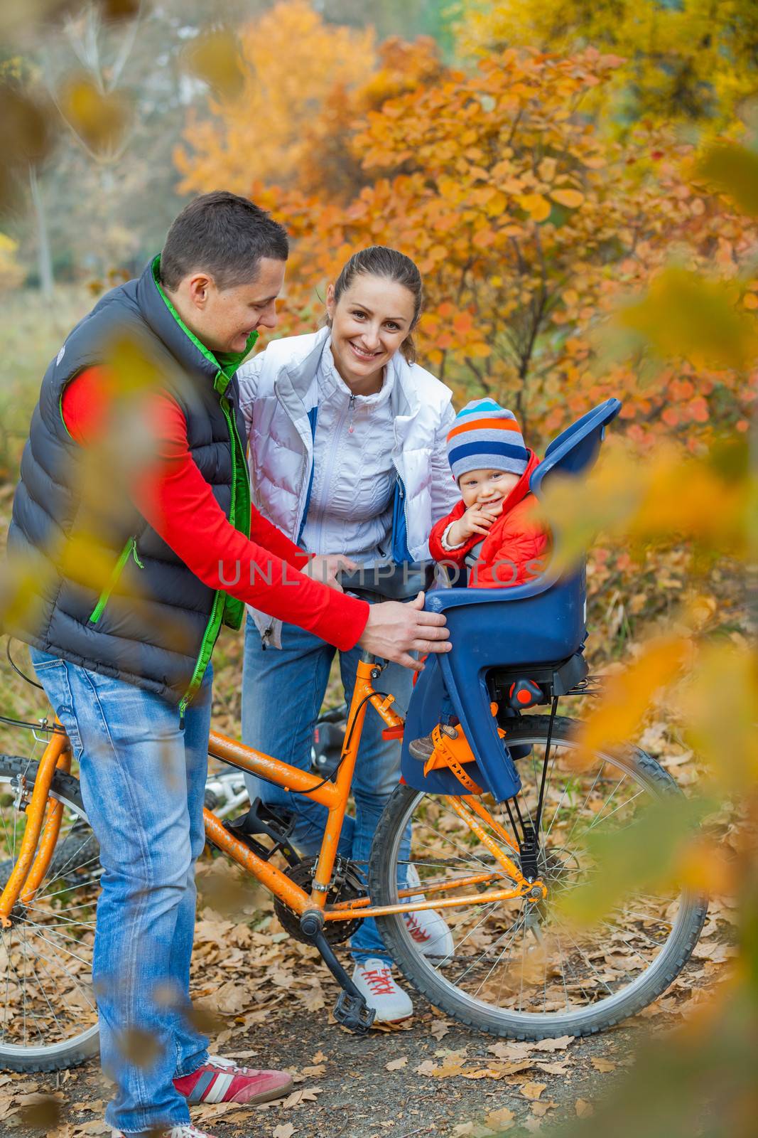Family with baby on bikes in the autumn park.