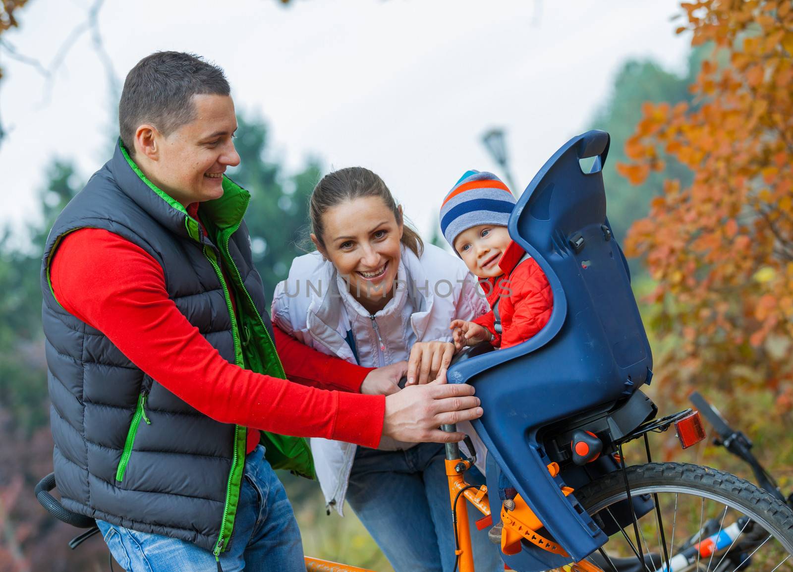 Family with baby on bikes in the autumn park.