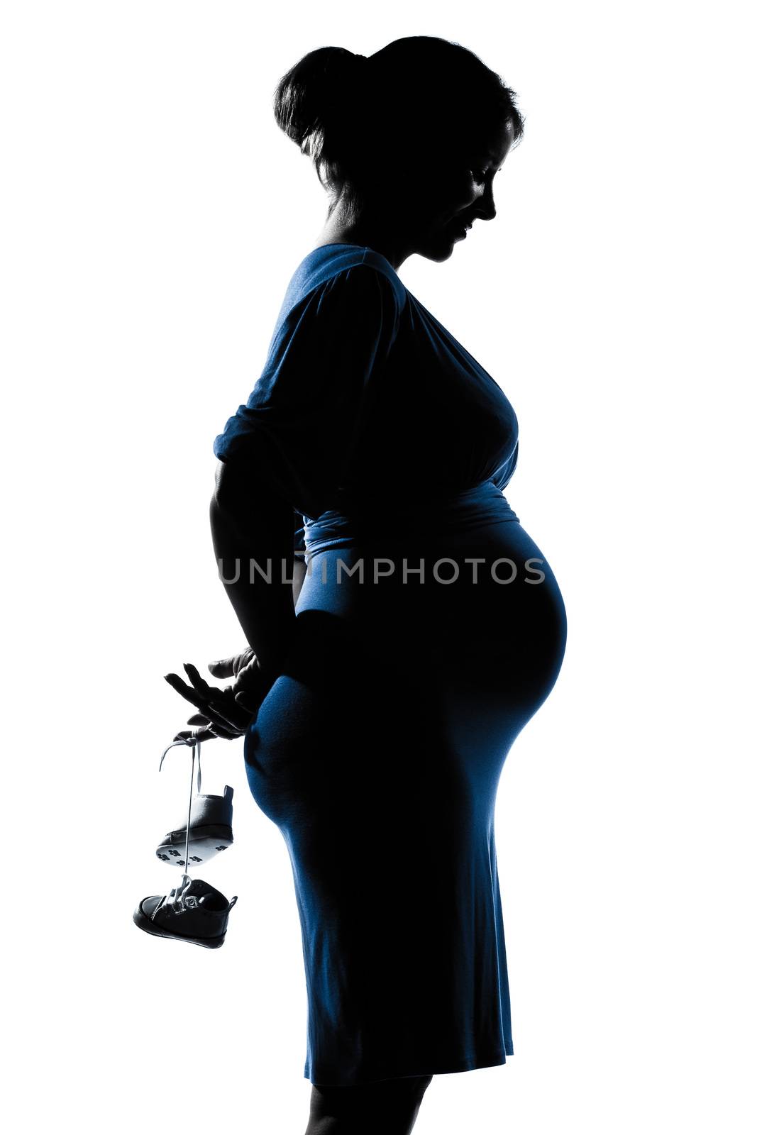 beautiful caucasian pregnant woman holding baby shoes in silhouette on studio isolated white background