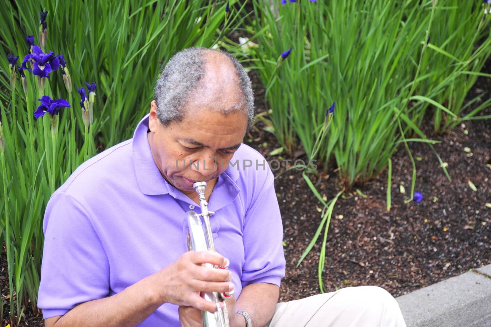 African American jazz musician blowing his flugelhorn outside.