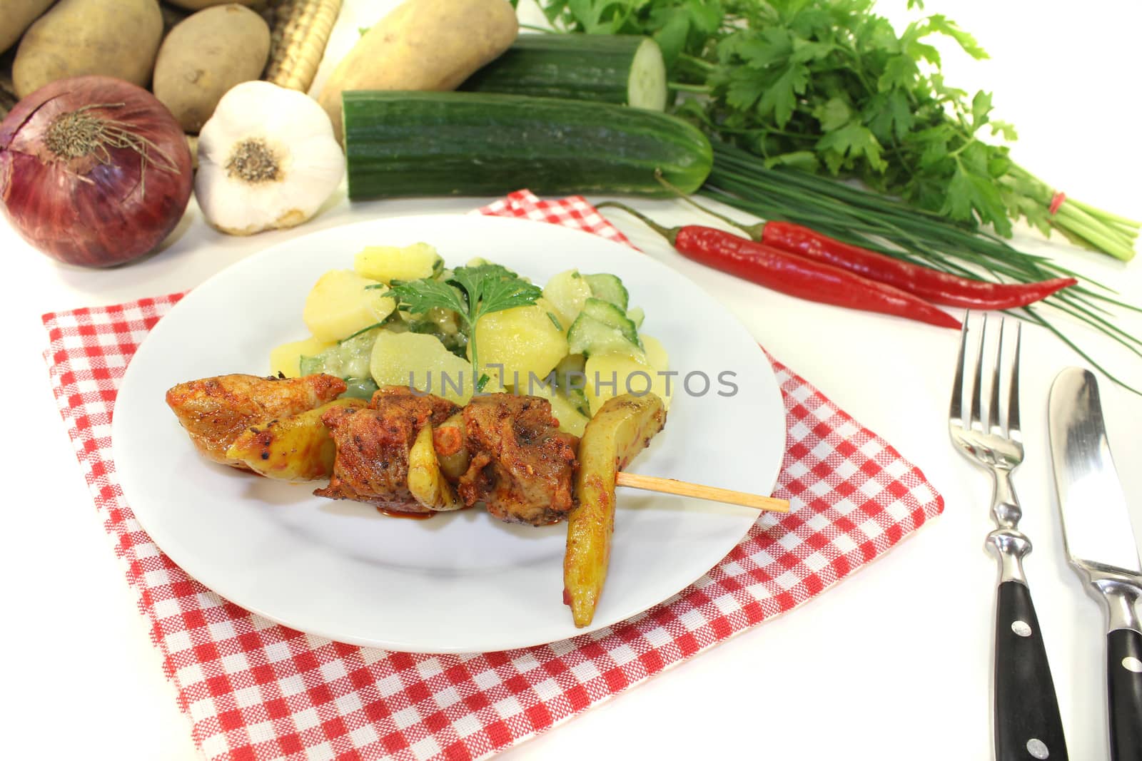 Potato-cucumber salad with fire skewers and parsley on a light background