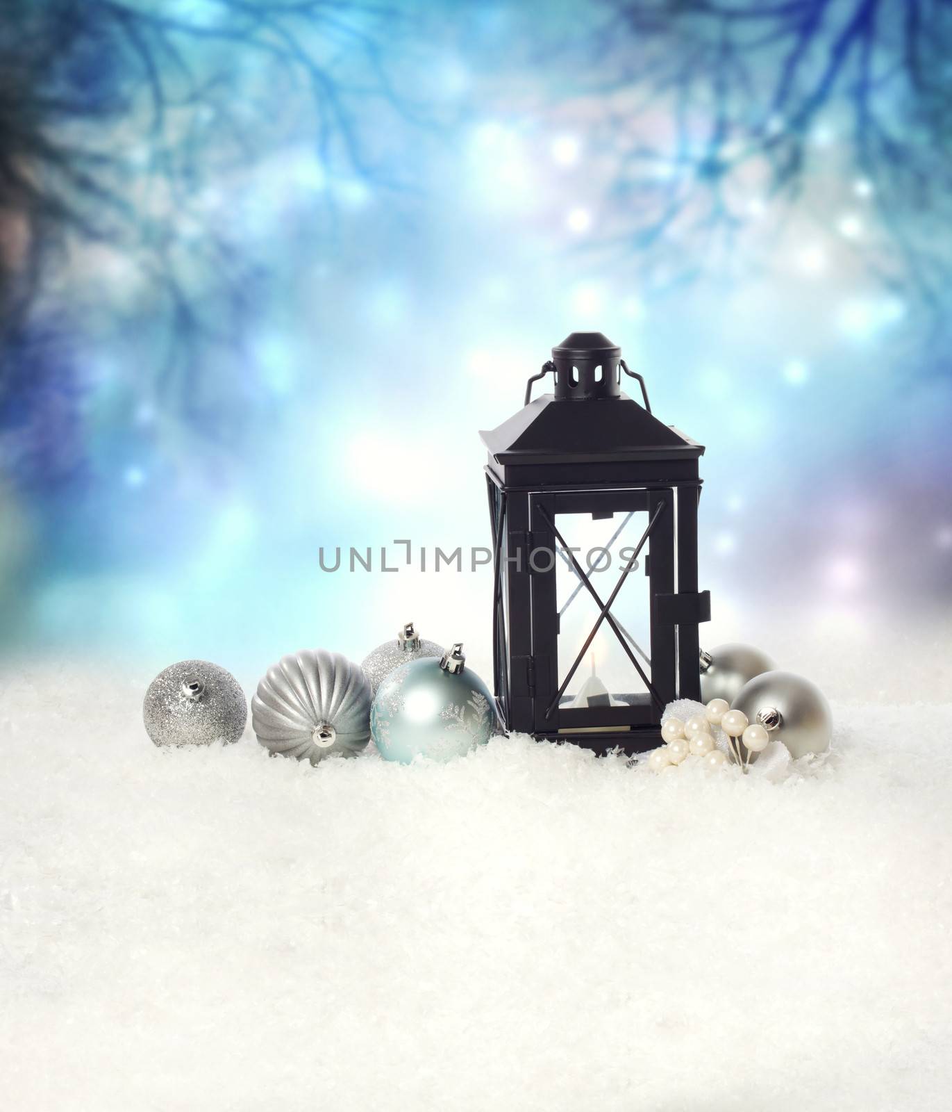 Christmas lantern and ornaments on the snow in a blue shinning night