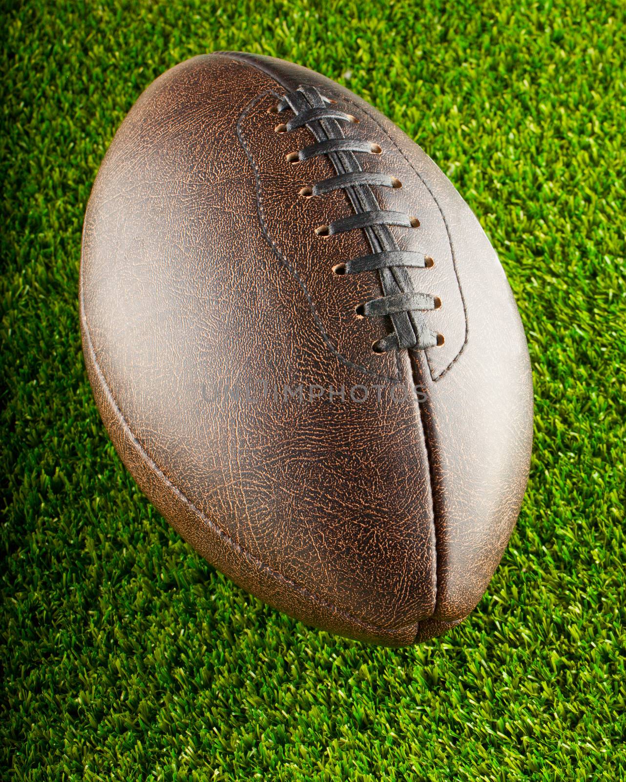 Brown leather football over a background of green grass