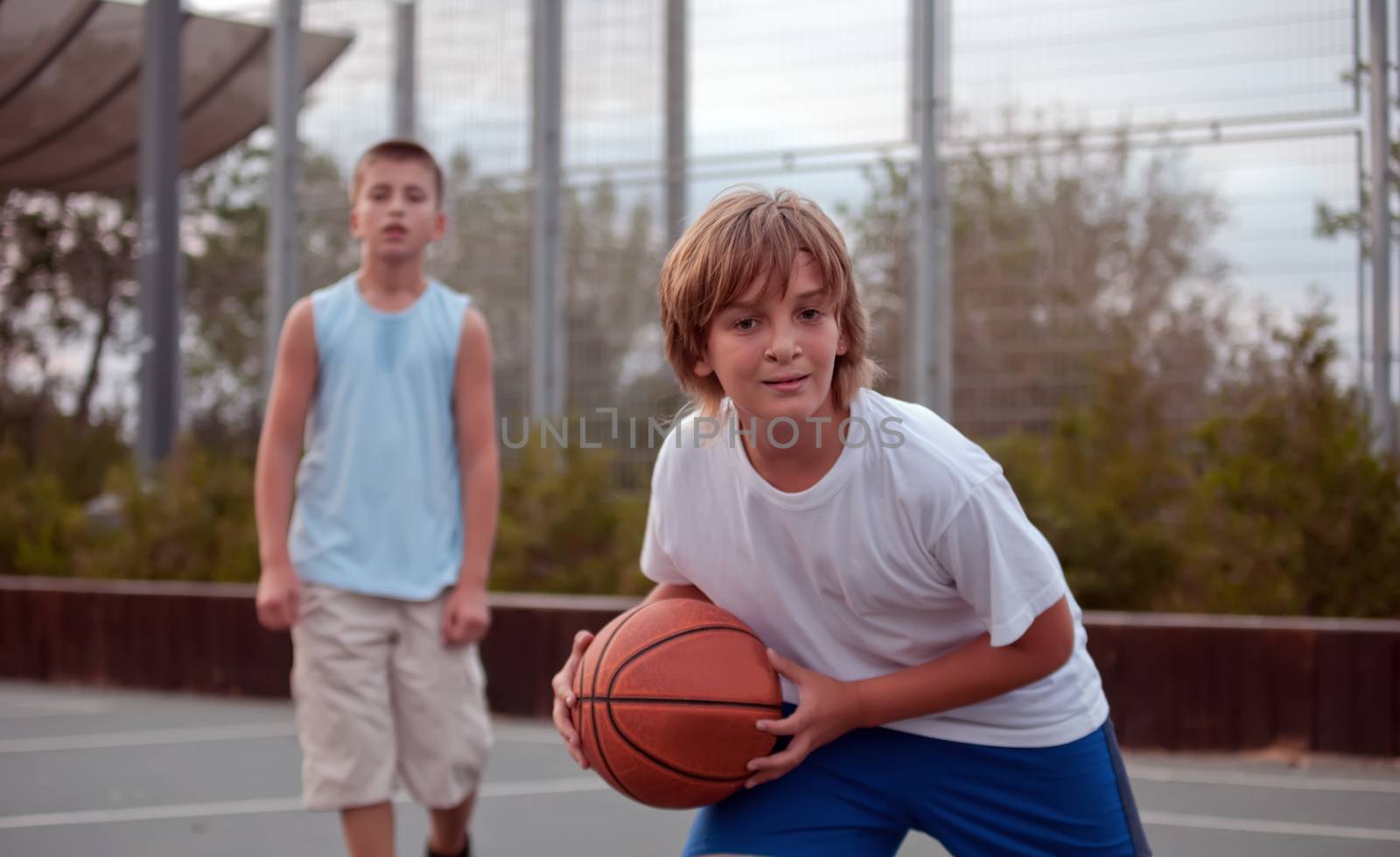 Kids play basketball in a school. by LarisaP