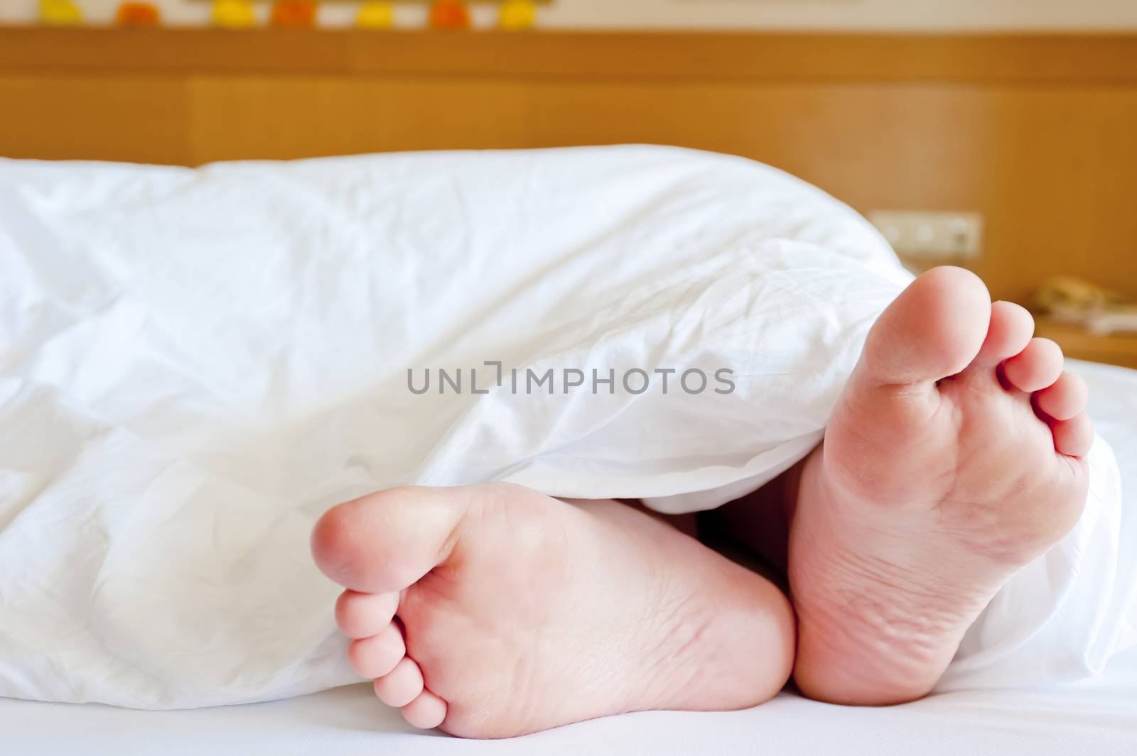 Beautiful female legs peeking out from under the blankets of snow-white